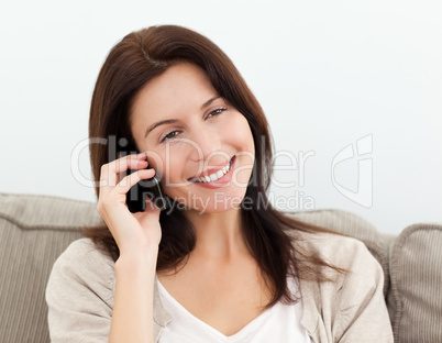 Happy woman on the phone sitting on the sofa