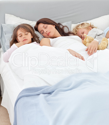 Serene mother sleeping with her children in her bed