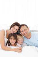 Portrait of a joyful family sitting on the bed