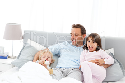 Handsome man with lying on his bed with his children at waiking