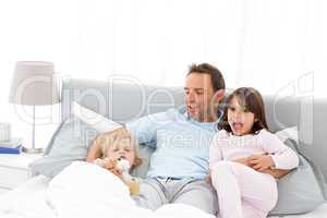 Handsome man with lying on his bed with his children at waiking