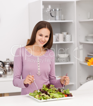 Pretty woman preparing a salad standing in the kitchen