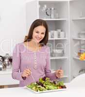 Pretty woman preparing a salad standing in the kitchen