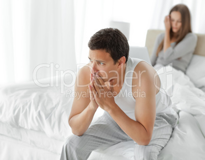 Man sitting on his bed while his girlfriend working on the lapto