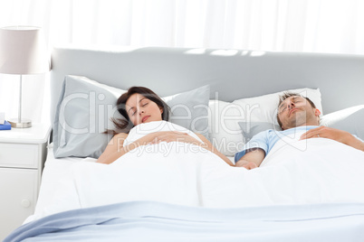 Lovely couple holding their hands while sleeping on their bed