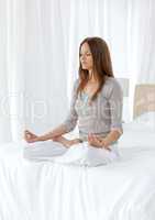 Quiet woman doing yoga exercises on the bed