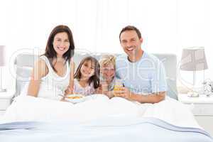 Happy family having breakfast together on the bed
