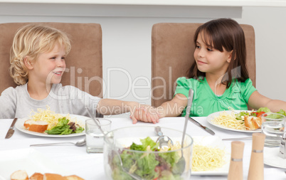 Cute brother and sister holding their hands before lunch