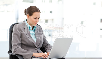 Cute businesswoman working on the laptop sitting at her desk