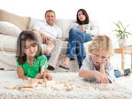 Proud parents looking at their children playing with dominoes on