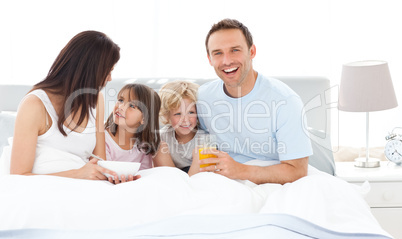 Happy dad having breakfast with his family on his bed