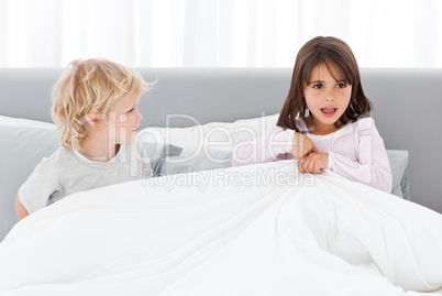Adorable children playing together on their parents' bed