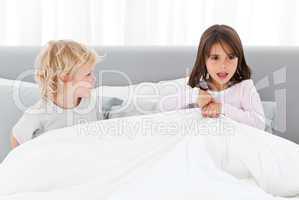 Adorable children playing together on their parents' bed