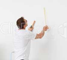 Handsome man looking at a wall with ruler and tools