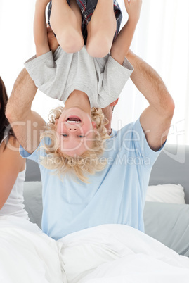 Cheerful boy playing with his father on the bed