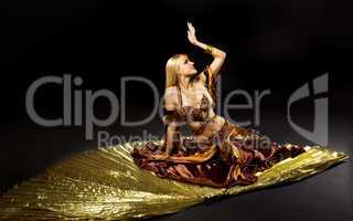 Young beauty woman lay on gold saber