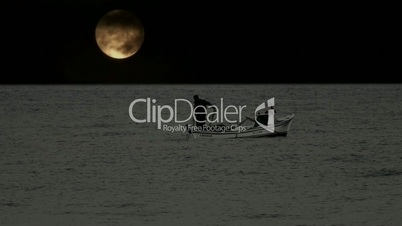 Lone fisherman pulling in his catch with full moon behind 2