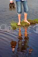 Barfuß am Wasser mit Schuhen in der Hand