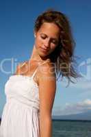Hübsche Frau am Strand mit weißem Kleid und braunen Haaren