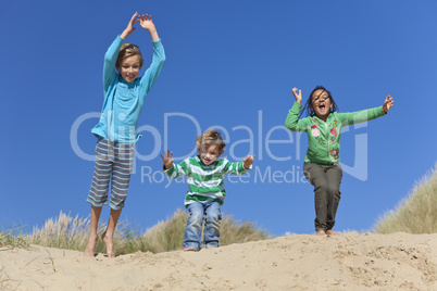Three Children Arms Raised Jumping Having Fun on Beach