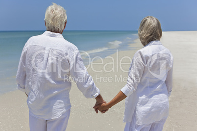 Senior Couple Holding Hands & Looking To Sea on Beach