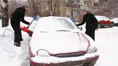 3 man cleans a car from the snow