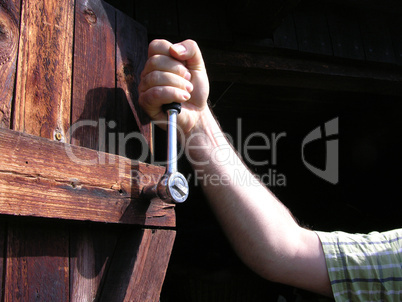 Auschnitt Hand mit Ratsche an Holztür