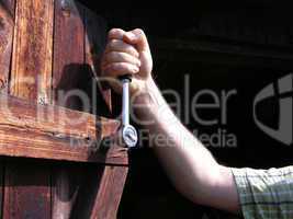Auschnitt Hand mit Ratsche an Holztür