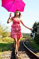 Frau mit roten Schirm balanciert auf Schienen 982