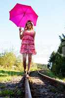 Frau mit roten Schirm balanciert auf Schienen 985