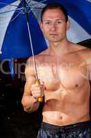 Junger Mann mit Regenschirm im Regen 358