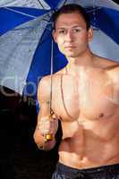Junger Mann mit Regenschirm im Regen 359
