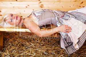 Junge blonde Frau im Dirndl liegt auf Holzbank 157