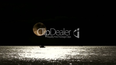 Lone fishing boat set against timelapse full moon
