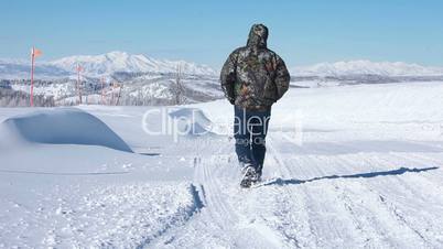 Man walking down snow covered mountain road HD 8431