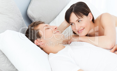Happy couple lying down together on their bed