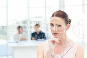 Serious businesswoman looking at the camera while her coworkers