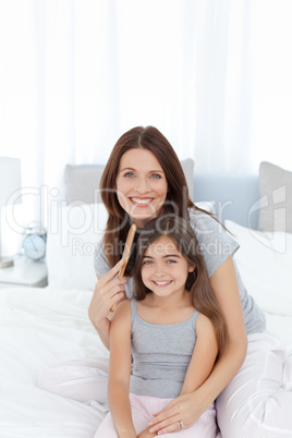 Woman brushing her daughter hair