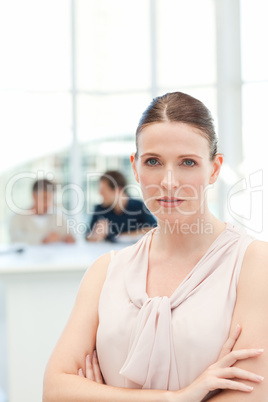 Serious businesswoman looking at the camera while her coworkers