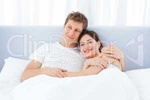 Man hugging his girlfriend on their bed