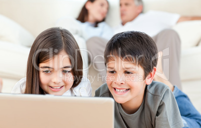Lovely children watching a movie on their laptop at home