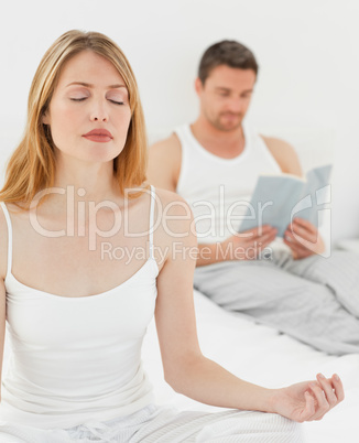 Woman practice yoga while her husband is reading