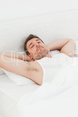 A relaxed man in his bed before waking up