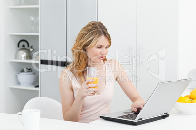 Woman drinking while she is looking at her laptop