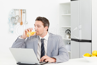 Businessman drinking while he is looking at his laptop