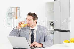 Businessman drinking while he is looking at his laptop