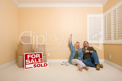 Couple on Floor Near Boxes and Sold Real Estate Signs