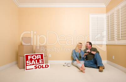 Couple on Floor Near Boxes and Sold Real Estate Signs