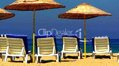 Sun loungers on an empty beach with clear blue sky