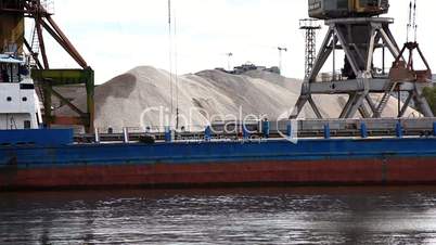 Crane unload gravel from barge on river